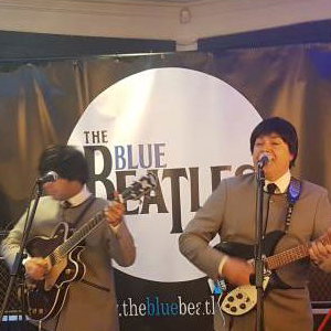The Blue Beatles Duo performing in grey collarless suits