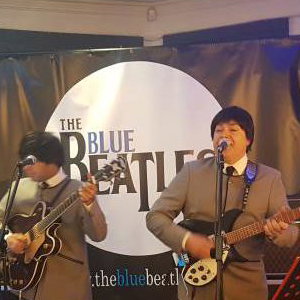 The Blue Beatles Duo performing in grey collarless suits