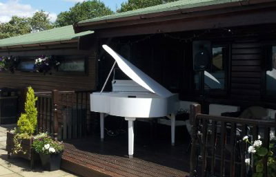A wedding ceremony outside with the grand piano at Flaxbourne Gardens
