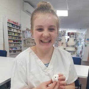 Young girl smiling during making her manikin at one of our Junior workshops.
