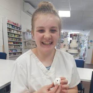 Young girl smiling during making her manikin at one of our Junior workshops.